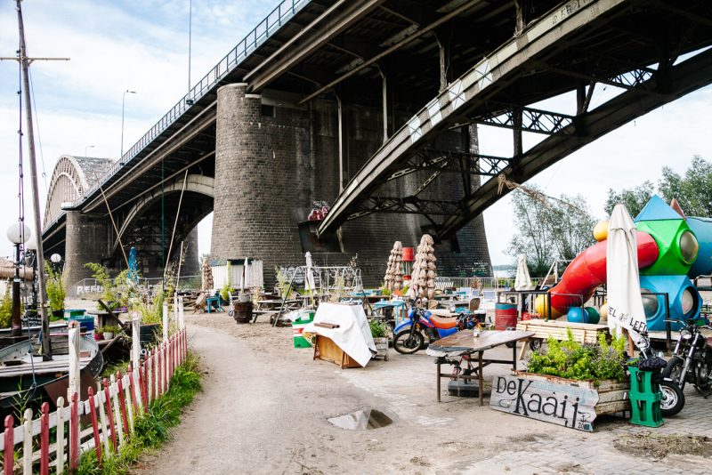 For festival and summer vibes, you want to be at De Kaaij. You will find a mishmash of picnic tables, umbrellas, stretch tents, a ship's deck and various food trucks, right under the Waal bridge. One of the super cozy things to do in Nijmegen, if you want to walk with your feet through the sand on a sunny day. 