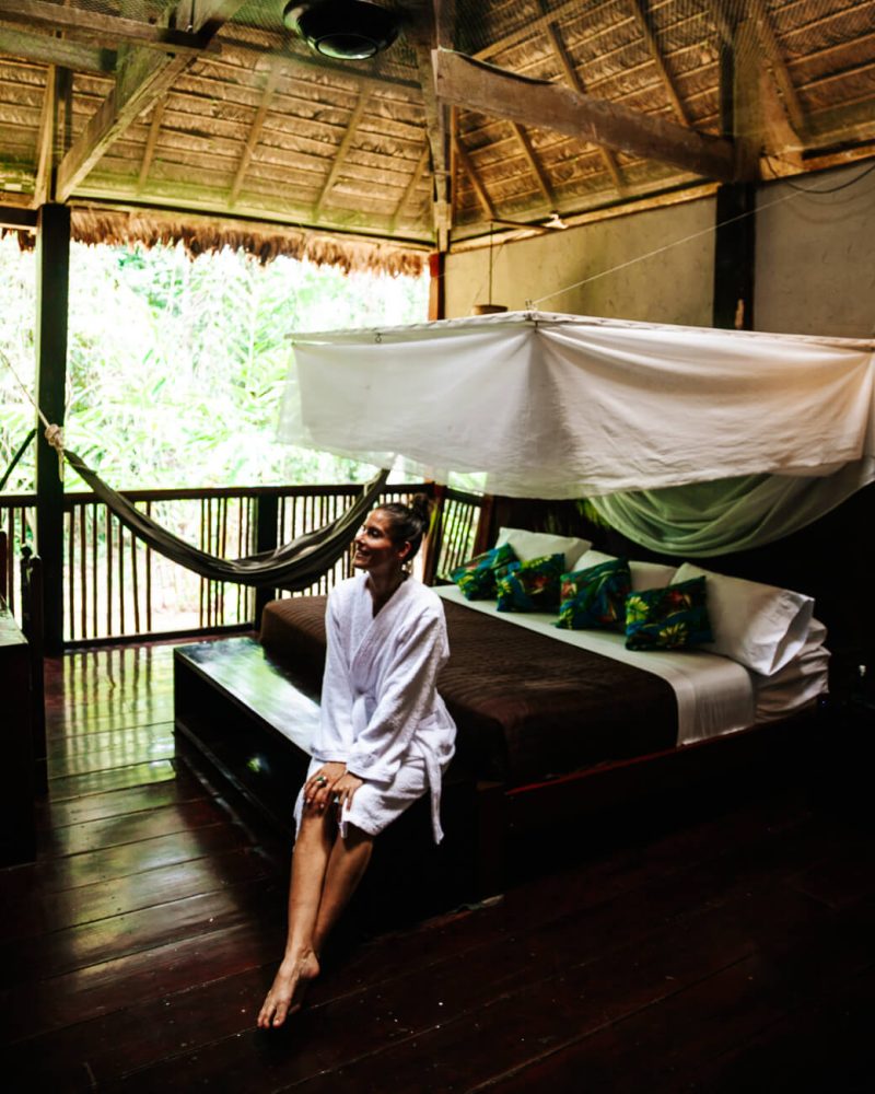 Deborah on bed in roo of  Rainforest Expeditions jungle lodge in Peru.